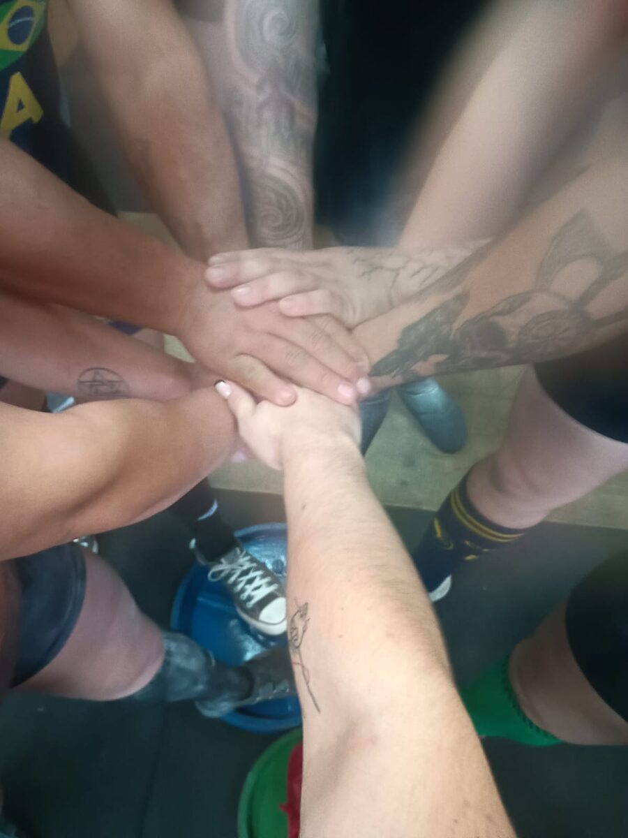 Mãos da equipe unidas antes da competição de powerlifting