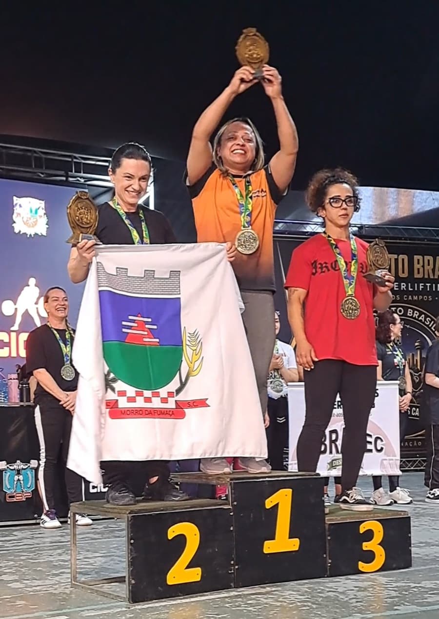 Viviane Maris erguendo o troféu no alto do pódio do Campeonato Brasileiro de Powerlifting